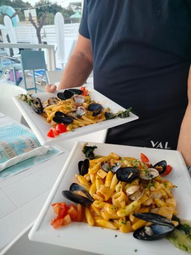a person sitting at a table with two plates of food at Hotel Miramare in Gallipoli