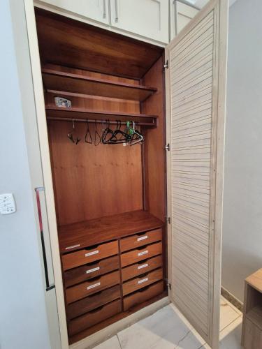 a closet with wooden cabinets and drawers at Quarto e Sala com Estilo e Conforto in Vitória