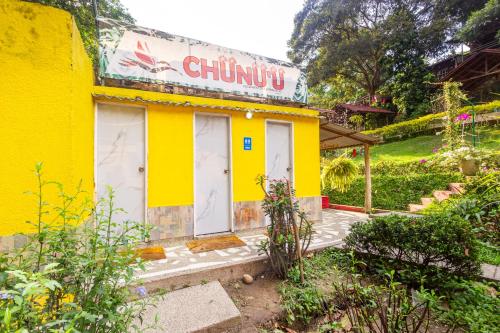 a yellow building with white doors and a sign on it at MINCA Chunuu - glamping - coworking MINCA in Minca