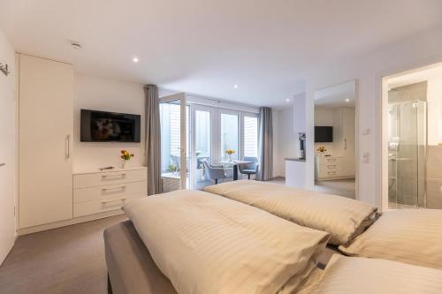 a white bedroom with two beds and a table at Haus-Andersen-Ferienwohnung-2 in Norderney