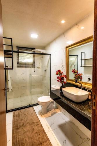 a bathroom with a sink and a toilet and a mirror at Casa Villa Fontana - Condomínio à beira-mar e próximo ao aeroporto - Praia de Itapuã in Salvador