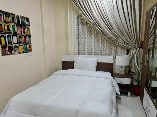 a bedroom with a white bed and a window at العربي للشقق المفروشة in Salalah