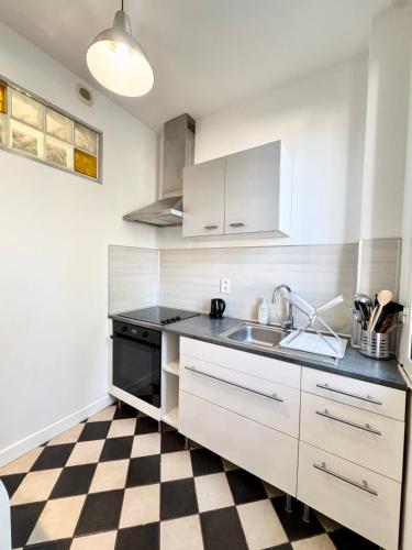 - une cuisine avec des placards blancs, un évier et un sol en damier dans l'établissement Confort & tranquillité - Centre de Lorient, à Lorient