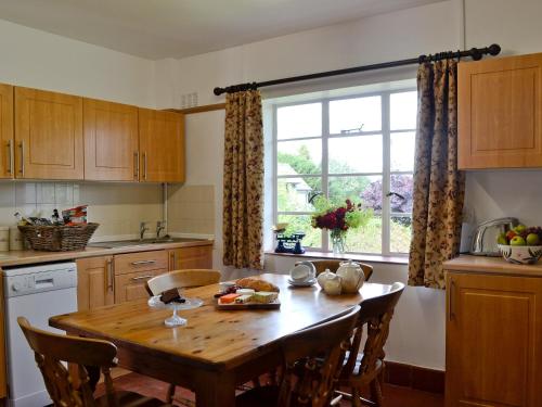 a kitchen with a wooden table and a window at The Old Post Office in Eaton Bishop