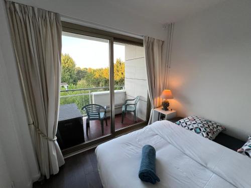 ein Schlafzimmer mit Bett und Blick auf einen Balkon in der Unterkunft Arsène 3 l'Hermitage in Le Touquet-Paris-Plage