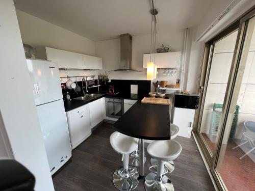 eine Küche mit einem schwarzen Tisch und weißen Geräten in der Unterkunft Arsène 3 l'Hermitage in Le Touquet-Paris-Plage