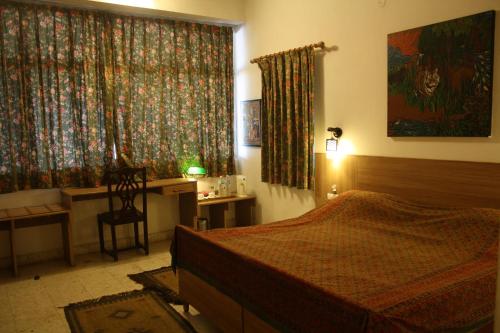 a bedroom with a bed and a desk and a window at Ivy Suites in Bhopal