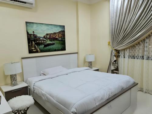 a white bedroom with a bed and a window at العربي للشقق المفروشة in Salalah