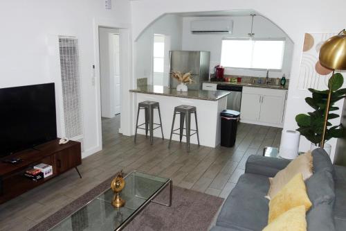 a living room with a couch and a table and a kitchen at Casa Mid City - Centrally Located 1BR Getaway with Private Yard in Los Angeles