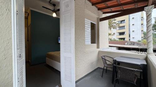 a room with a table and a bed on a balcony at Suíte 15 • Praia das Pitangueiras in Guarujá