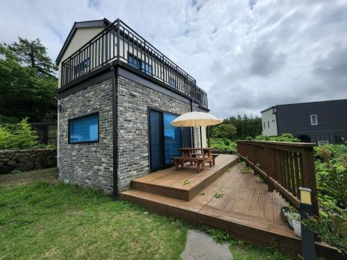 a small house with a wooden deck with an umbrella at Hallim House in Jeju