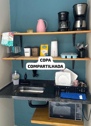 a kitchen shelf with a counter top with a microwave at Suíte 14 • Praia das Pitangueiras in Guarujá