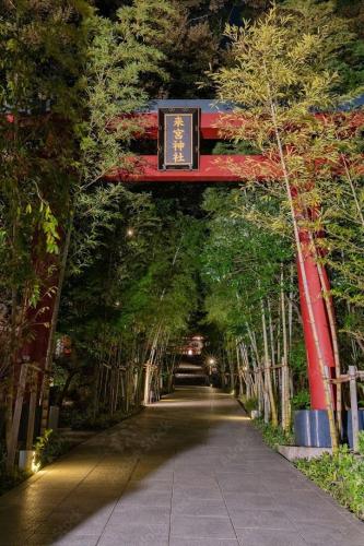 a path through a forest of trees with a sign at Apt熱海 in Atami