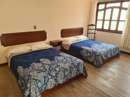 ein Hotelzimmer mit zwei Betten und einem Fenster in der Unterkunft Hotel Las Violetas in Zacatlán