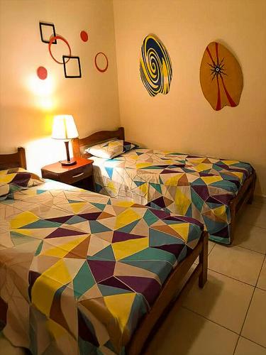 a bedroom with two beds with a colorful comforter at Casa Playa Tonsupa Tu paraíso frente al mar Internet Alta Velocidad Smart TV Netflix in Tonsupa