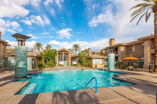 a swimming pool with a palm tree and buildings at The Cliffs at Peace Canyon in Las Vegas