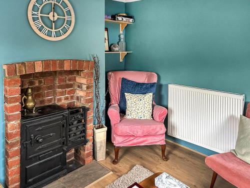 a living room with a chair and a clock on the wall at Tiddles Corner in Braunston