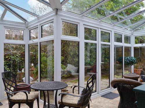 a conservatory with a table and chairs and glass doors at Ty Newydd in Beddgelert