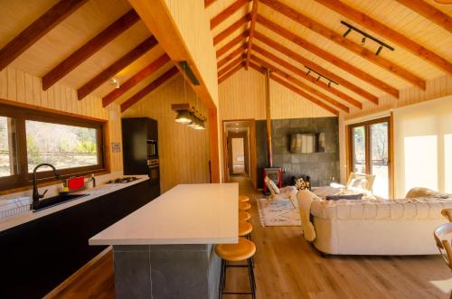 a kitchen and living room with wooden ceilings and a couch at Casa Las Raíces - Relajo con tinaja y vista al volcán, a minutos de Corralco in Malalcahuello