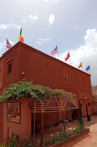 a red building with flags on top of it at Gite le Calme café Restaurant Pizzeria in Bou Tharar