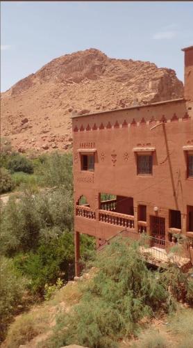 a building in the middle of a field with a mountain at Gite le Calme café Restaurant Pizzeria in Bou Tharar