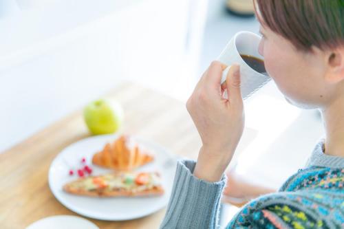 a woman drinking a cup of coffee with a plate of food at Marina blue zushi in Zushi