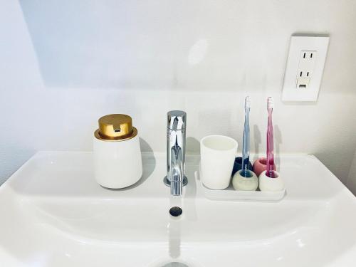 a white sink with toothbrushes and other items on it at Marina blue zushi in Zushi