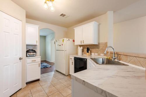 a kitchen with white cabinets and a sink and a refrigerator at Gorgeous 2story Home with 4 bedrooms in Buda