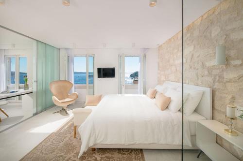 a white bedroom with a large bed and a chair at Beautiful Hvar Villa 4 Bedrooms Villa Hvar Majestic Resort Centre Location & Wonderful Sea Views in Hvar