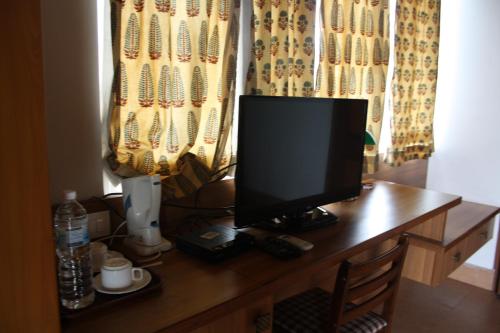 a computer monitor sitting on top of a wooden desk at Ivy Suites in Bhopal