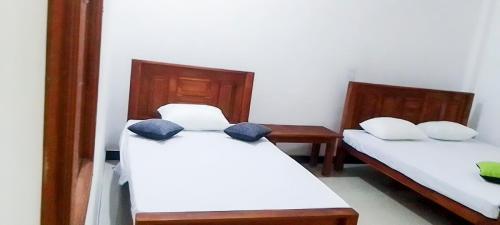 two beds in a room with white sheets and blue pillows at Igloo Tourist Homestay Anuradhapura in Anuradhapura