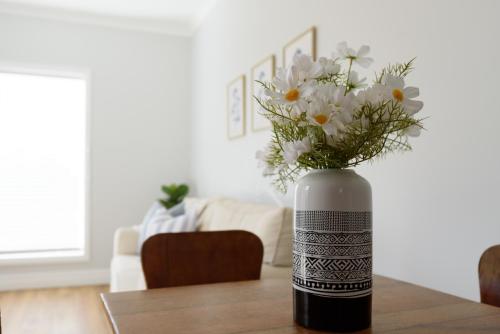 a vase filled with white flowers on a table at Cosy Self-Contained Unit with QBed, Parking & Wifi in Ilfraville