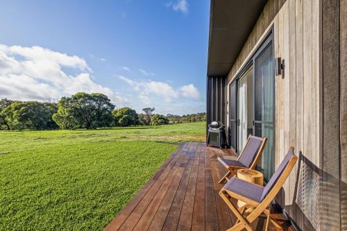 two chairs on a porch with a grass field at Chalet Coast Walburra Brook in Metricup