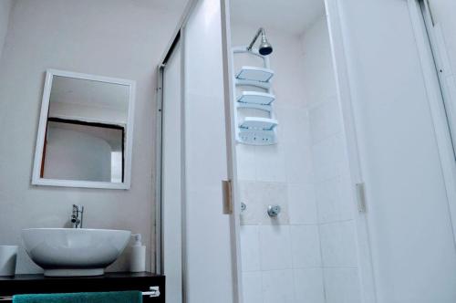 a white bathroom with a sink and a mirror at Casa SUR in Colonia de Venado