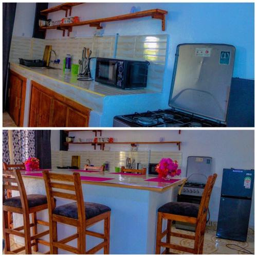 a kitchen with a stove and a counter with two chairs at jahazi homes -watamu in Watamu