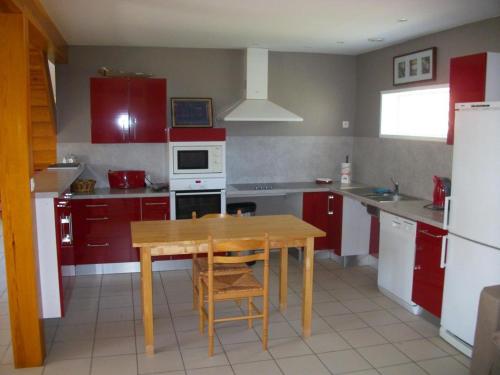 une cuisine avec une table en bois et des placards rouges dans l'établissement Gîte spacieux avec jardin, barque, et label tourisme handicap - Marais Audomarois - FR-1-376-72, à Saint-Omer
