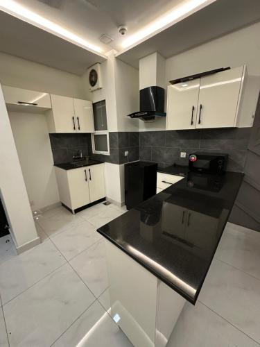 une cuisine avec des armoires blanches et un comptoir noir dans l'établissement One bed comfortable luxury apartment, à Dargai
