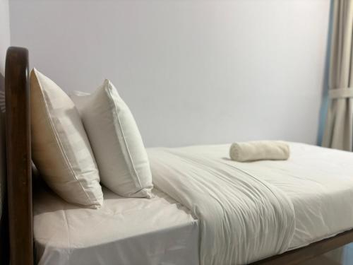 a bed with white sheets and pillows on it at Gaia Residences by Plush in Rawang
