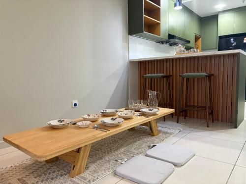 a wooden table with bowls and plates on it in a kitchen at Gaia Residences by Plush in Rawang