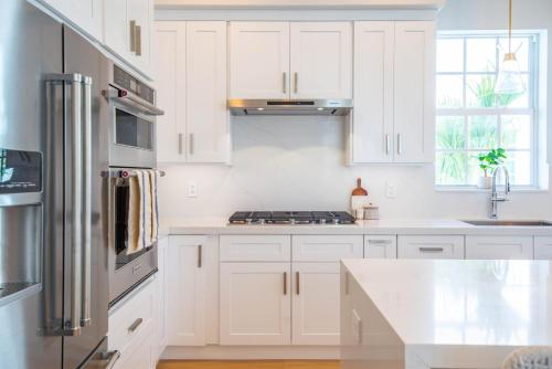 a white kitchen with white cabinets and a stove at Sea Glass Cove by SoFLA Vacations in Marathon