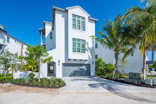 a white house with palm trees in front of it at Sea Glass Cove by SoFLA Vacations in Marathon