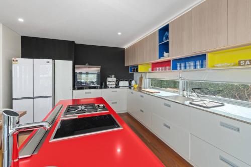 a red kitchen with white cabinets and a red counter top at 'Bulli Escape' Bright Beachfront Stay & Scenic Views in Bulli
