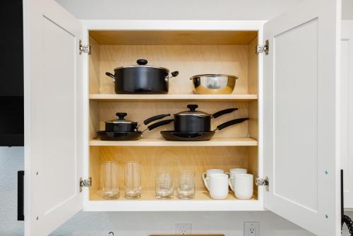 a cupboard with pots and pans and glasses at St Louis Premier Modern Vegas Escape Arts District & Patio in Las Vegas