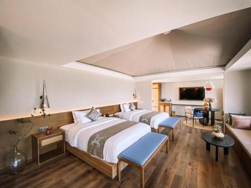 a hotel room with two beds and a couch at Shanyin Xijiang Rustic Luxury Resort Hotel in Bailian
