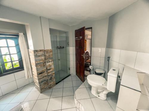 a bathroom with a toilet and a glass shower at Falésia Praia Hotel in Canoa Quebrada