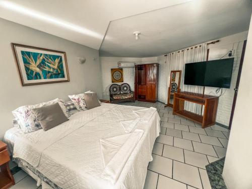 a bedroom with a bed and a flat screen tv at Falésia Praia Hotel in Canoa Quebrada