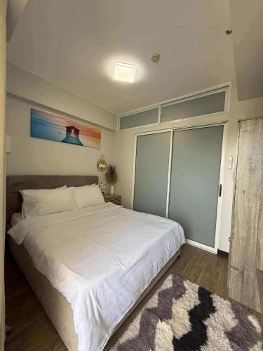 a bedroom with a large white bed and a rug at 1 BR Condo with balcony in Verdon Parc with Sea View in Sanghay