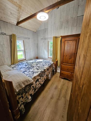 une chambre avec un lit dans une pièce en bois dans l'établissement Fun Place with a Sandy Beach for Swimming, Boating & Fishing, Featuring 1 House and 3 Cabins, à Fenelon Falls