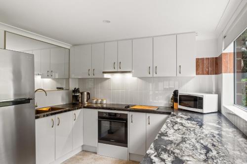 a kitchen with white cabinets and a microwave at Arcadia Dreaming Chalet Margaret River in Margaret River Town