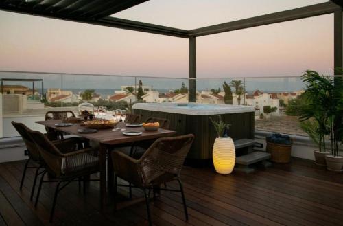una terrazza con tavolo, sedie e vasca idromassaggio di Magnificent Protaras Villa Villa Chelsea 3 Bedrooms Private Outdoor Pool a Protaras